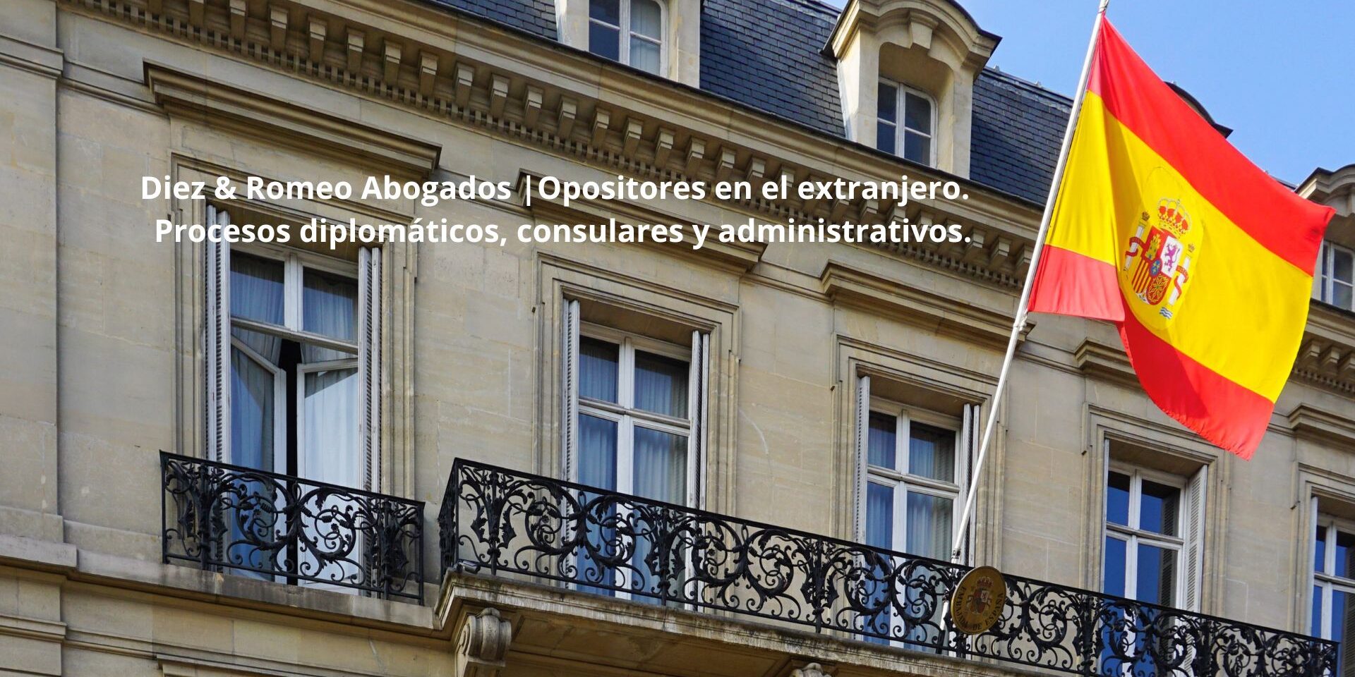 Fachada de una embajada española con la bandera de España, representando la asistencia jurídica internacional de Diez & Romeo Abogados a opositores residentes en el extranjero.