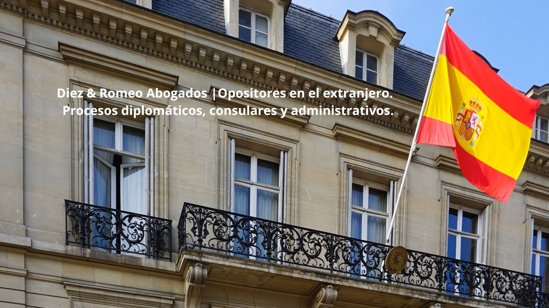 Fachada de una embajada española con la bandera de España, representando la asistencia jurídica internacional de Diez & Romeo Abogados a opositores residentes en el extranjero.